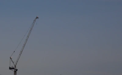 A sleek articulated boom lift extending high against a clear blue sky.