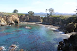 A hidden cove with crystal-clear water and rocky cliffs bathed in golden sunlight