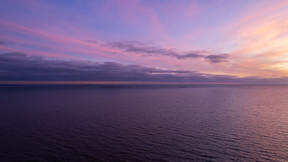 Una puesta de sol sobre un cuerpo de agua con nubes en el cielo