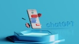 A digital illustration featuring a smartphone floating above a hexagonal platform, with gears and digital elements surrounding it. The screen displays a chatbot interface with various colored speech bubbles. The background is a solid light blue, emphasizing the technological theme. The text 'chatGPT' is displayed in 3D lettering on the right side.