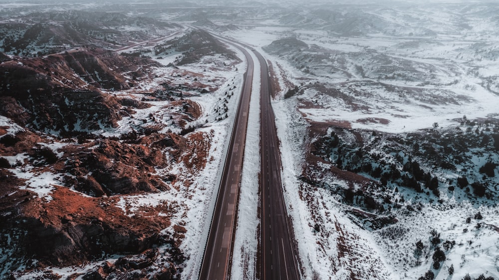 an aerial view of a road in the mountains covered in snow