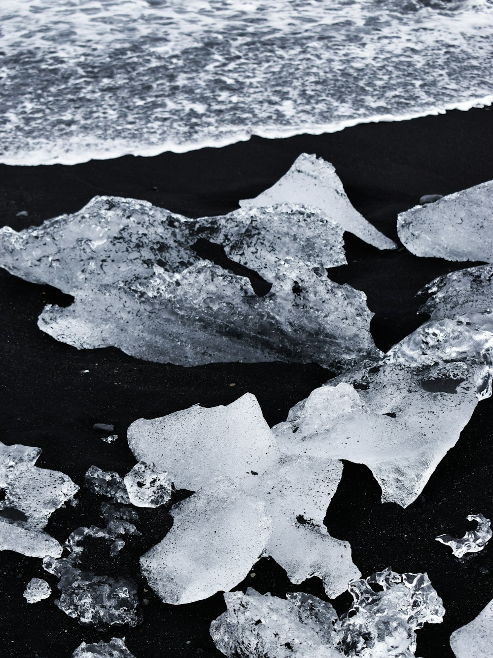 a black and white photo of ice on a beach