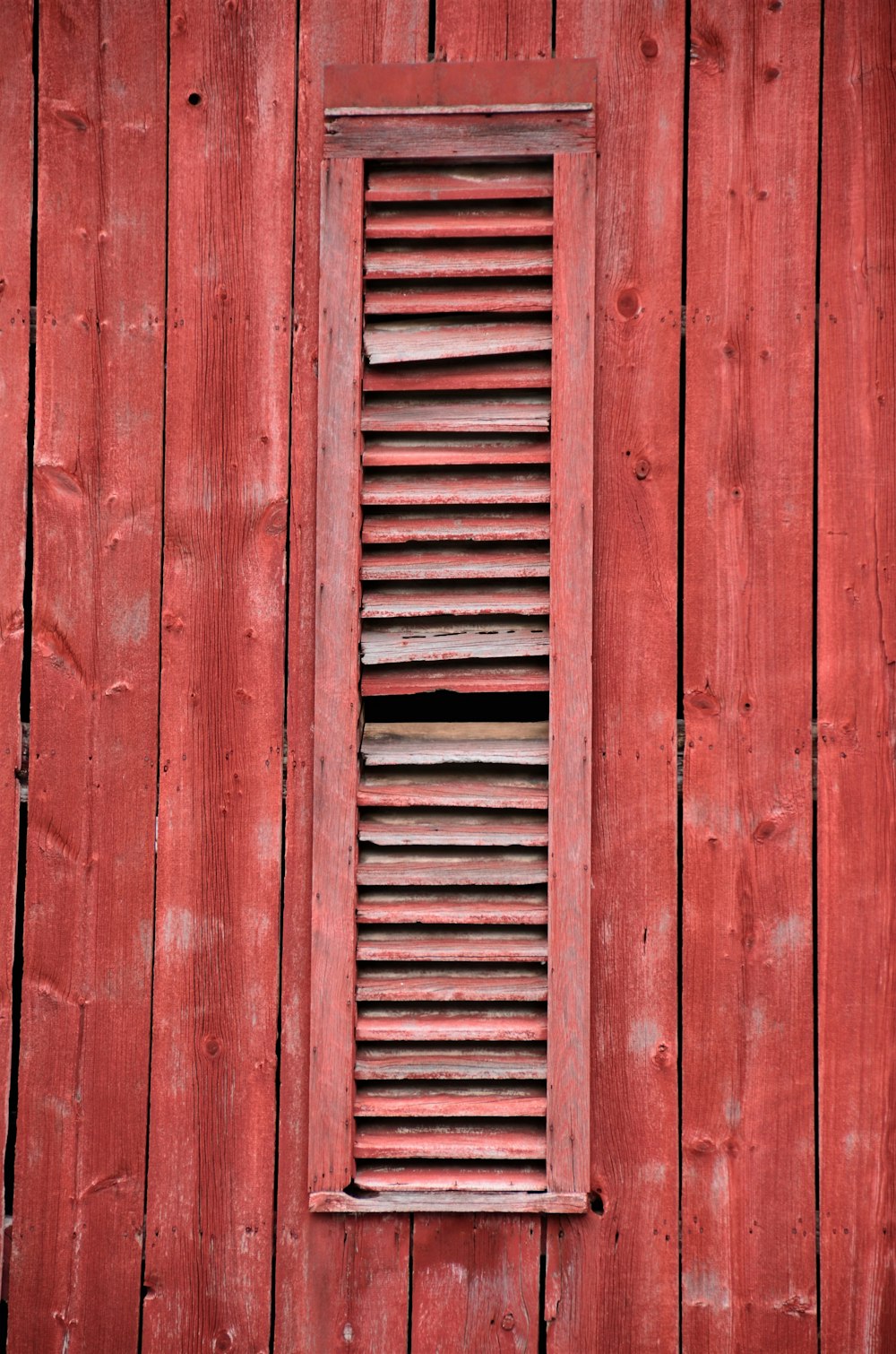 a red wall with a window and a wooden shutter