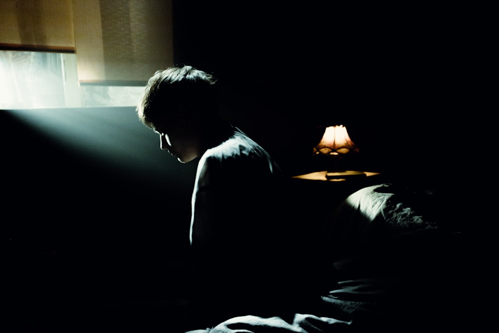 a person sitting on a bed in the dark