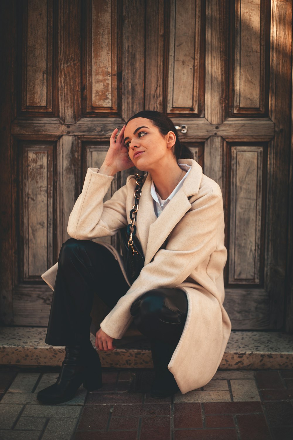 a woman sitting on the ground in front of a wooden door