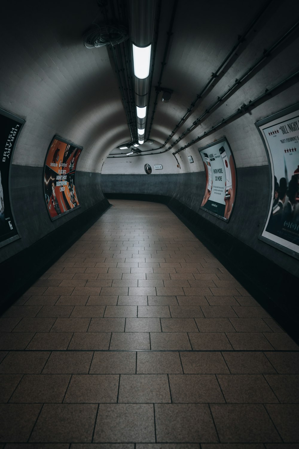 an empty subway tunnel with posters on the wall