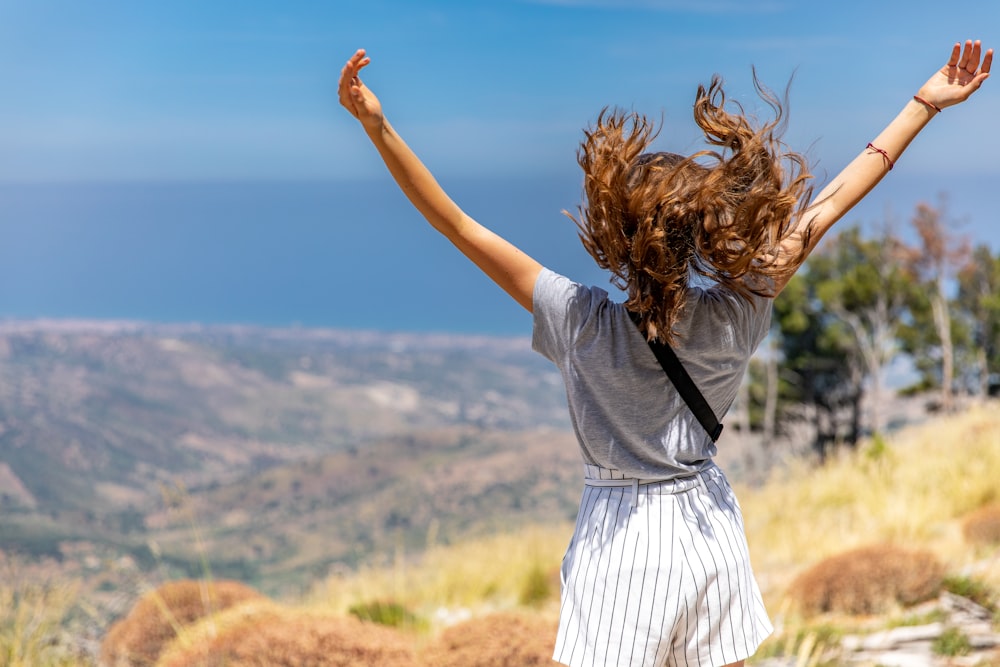 a woman with her hair in the air on top of a hill