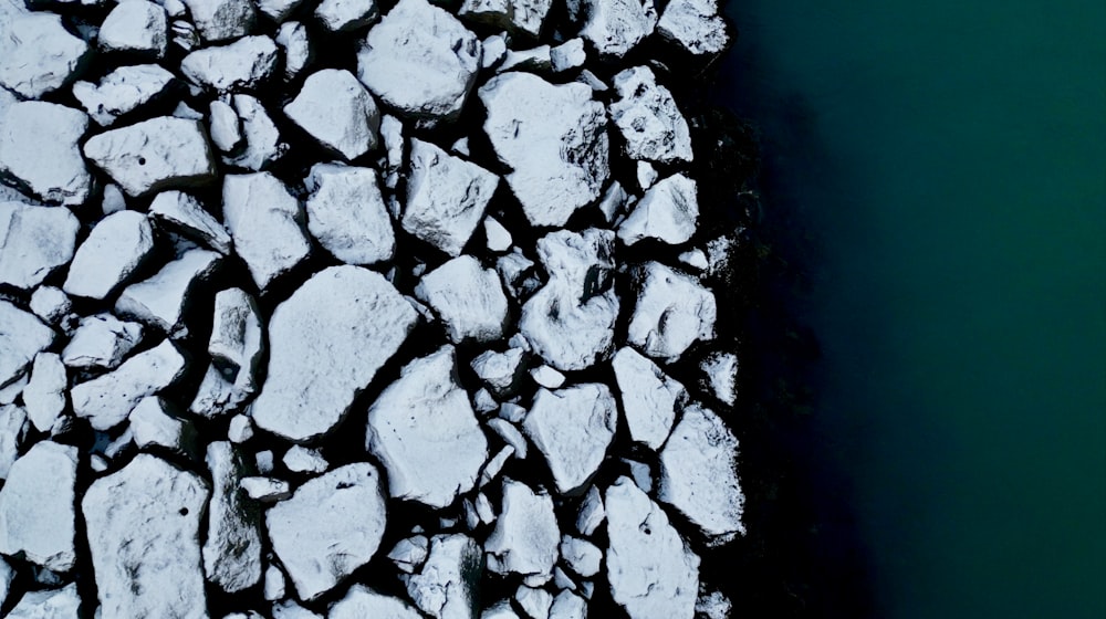 a large pile of rocks next to a body of water