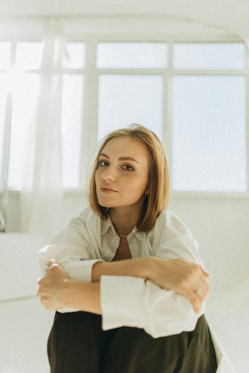 a woman sitting on the floor in front of a window