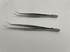 A set of stainless steel tweezers neatly arranged on a factory production line.