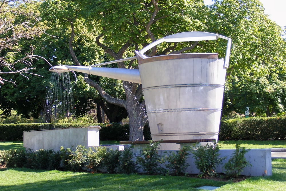 uma escultura de um balde e uma árvore em um parque