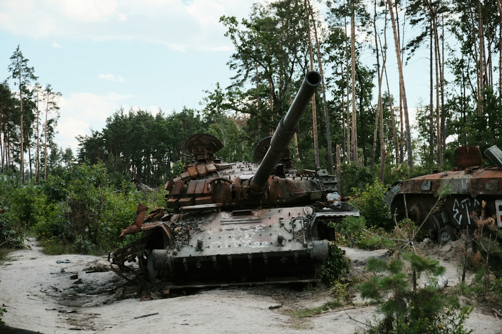 a rusted out tank sitting in the middle of a forest