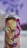 A spray can with vibrant and colorful artwork featuring a stylized human face with strong features. The face is adorned with bold colors including greens, reds, and purples, and an abstract background design complements the portrait.