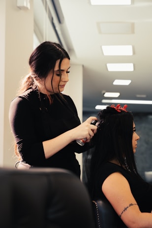 a woman cutting another woman's hair in a salon