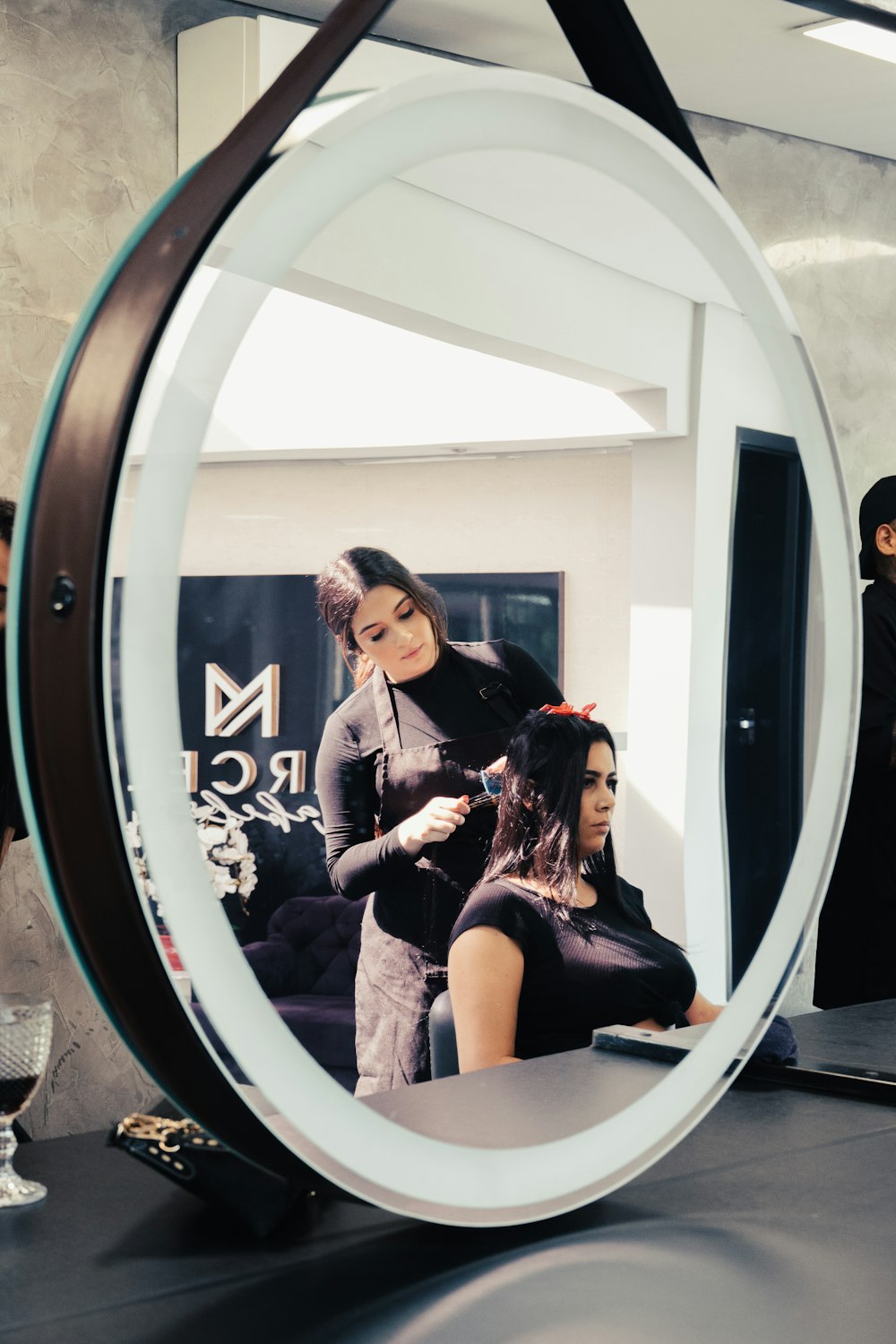 a woman getting her hair styled in a mirror