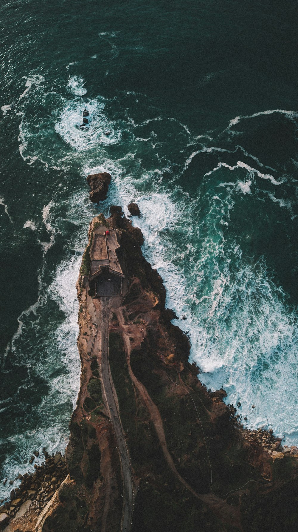 an aerial view of a lighthouse on a rocky shore