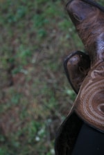 Close-up of a craftsman stitching intricate patterns on a leather cowboy boot.