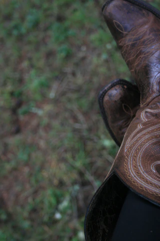 Close-up of cowboy boots tapping rhythmically on a wooden dance floor.