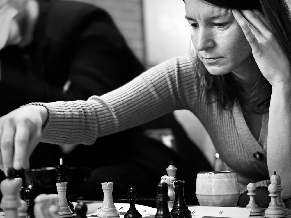 a woman sitting at a table playing a game of chess