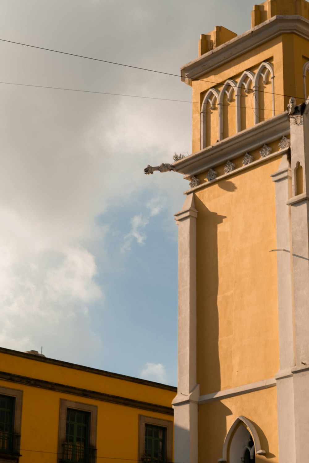 a tall yellow building with a clock on it's side