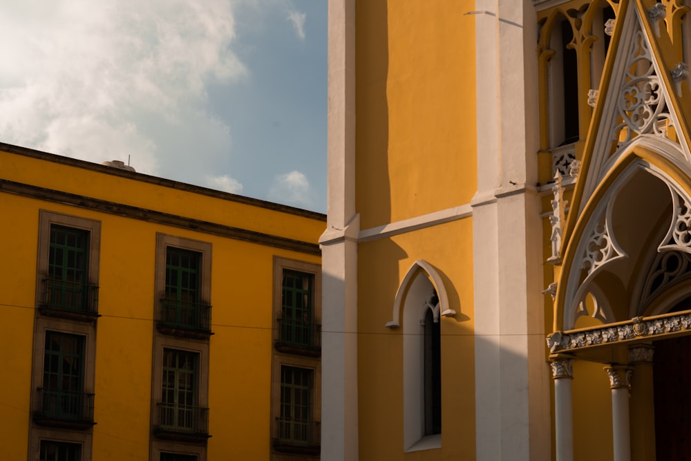 a tall yellow building with a clock on it's side