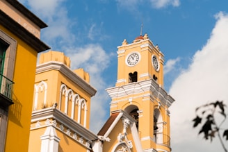 a yellow building with a clock on the front of it