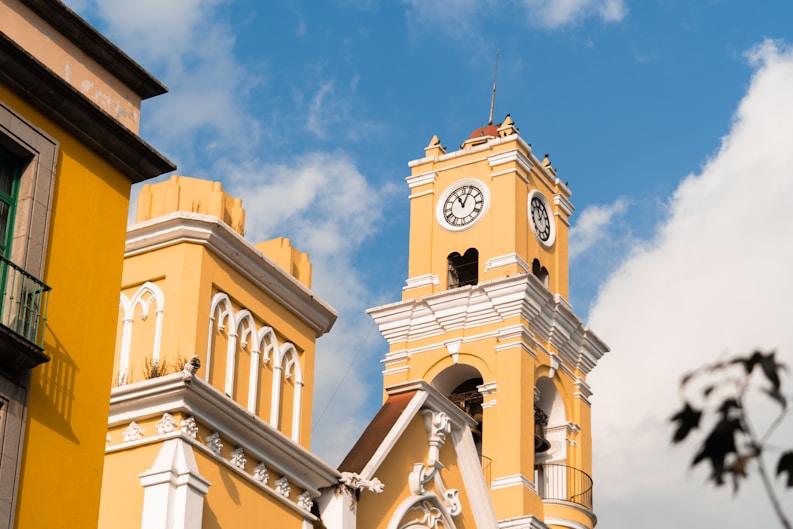 a yellow building with a clock on the front of it