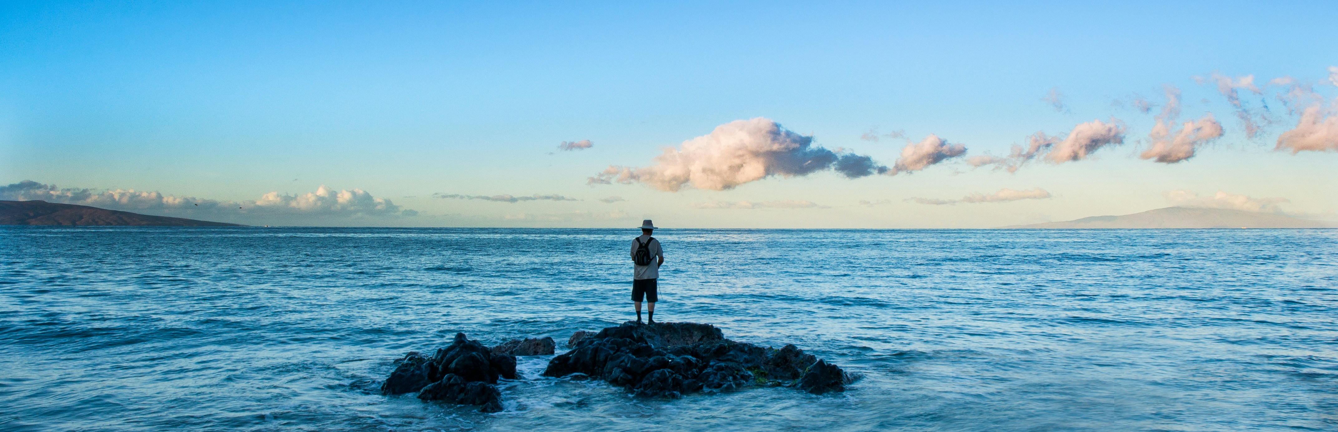 a person standing on a rock in the middle of the ocean