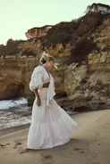 A dynamic slider image showing a model walking along the shore wearing a breezy beach cover-up.