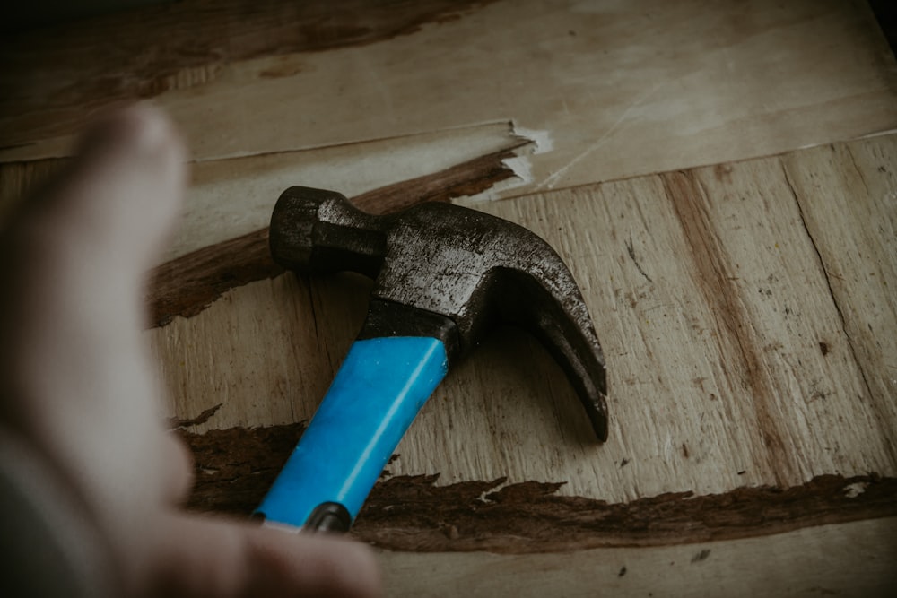 un martillo con un mango azul en un trozo de madera