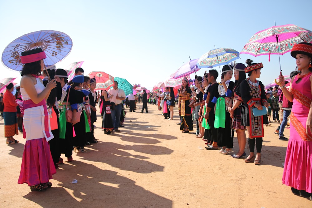 a large group of people with umbrellas on a dirt field