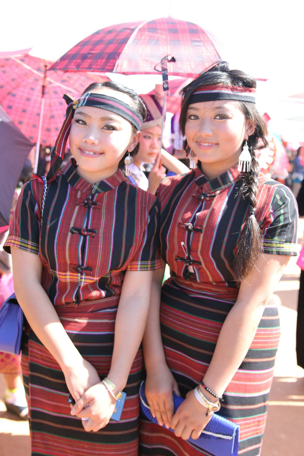 two young women standing next to each other under an umbrella