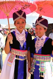 A group of queens and princesses in traditional dresses smiling warmly during a community event.