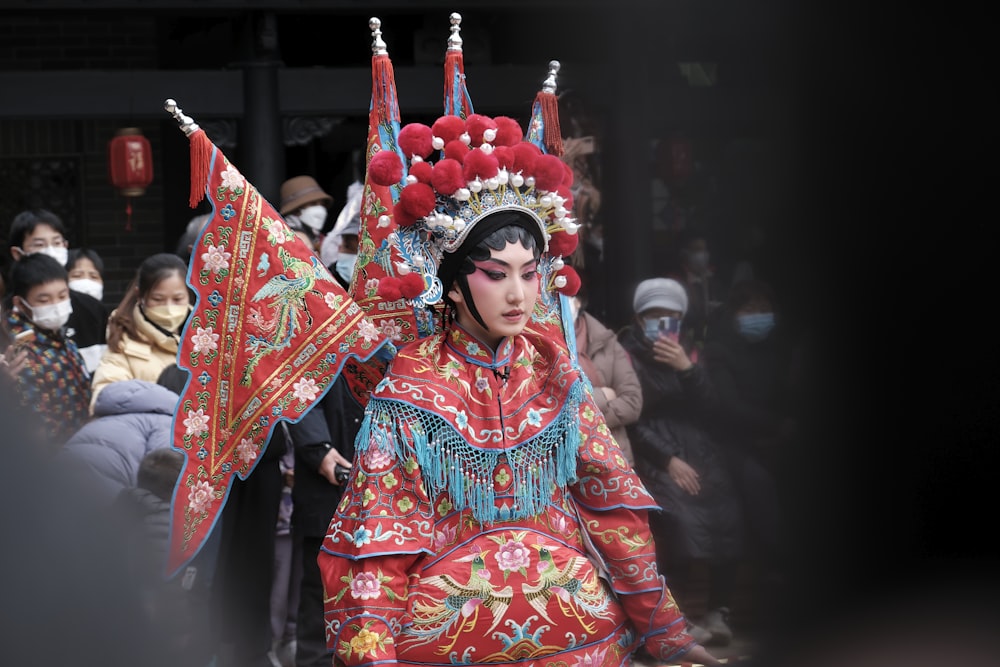 a woman dressed in a costume and headdress walking down a street