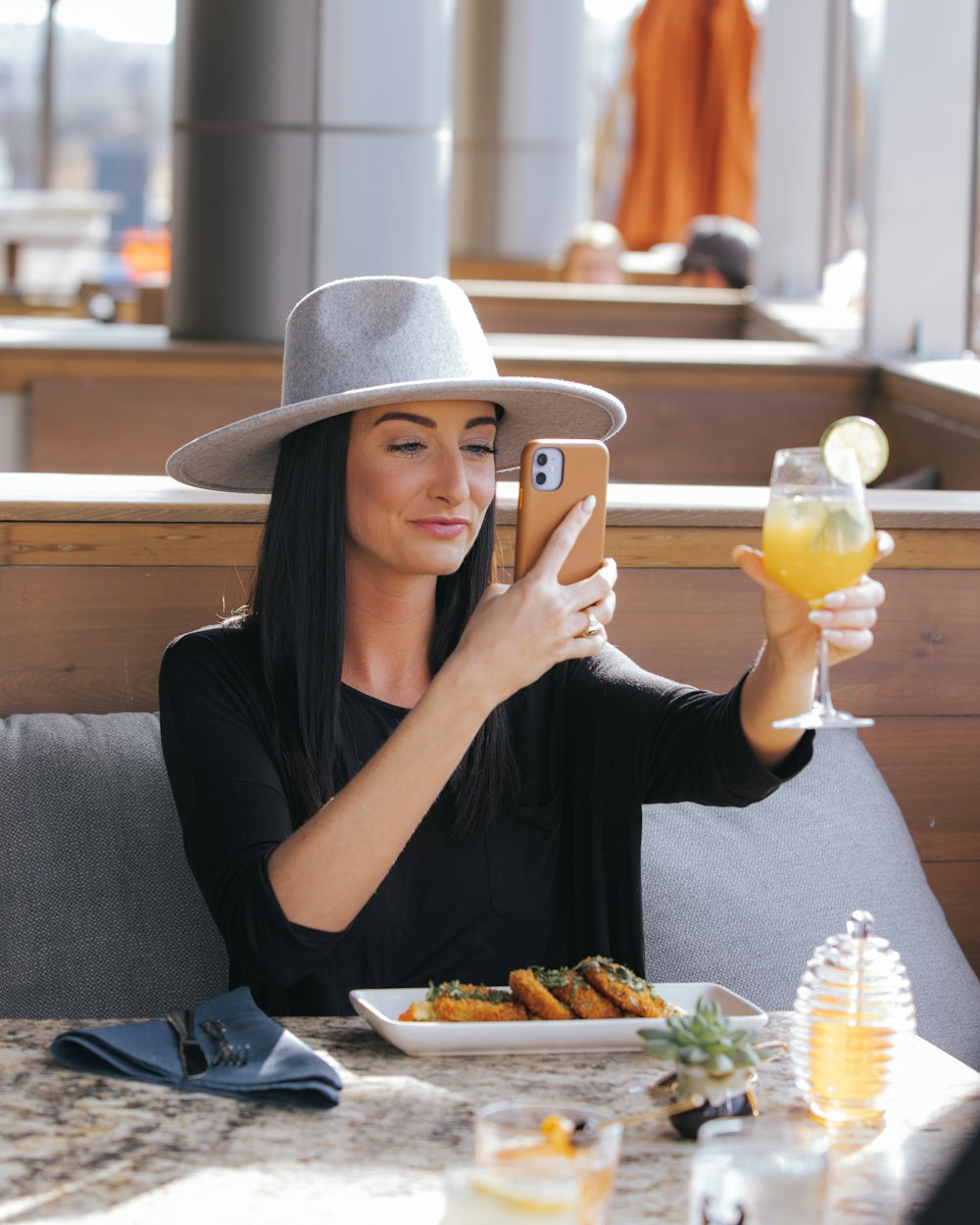 a woman sitting at a table taking a picture with her phone