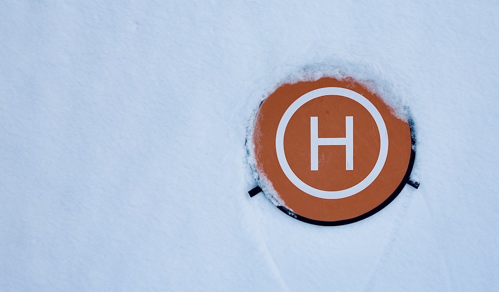 a circle with the letter h on it in the snow