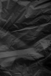 Artistic shot of a folded black matte hoodie with asphalt texture