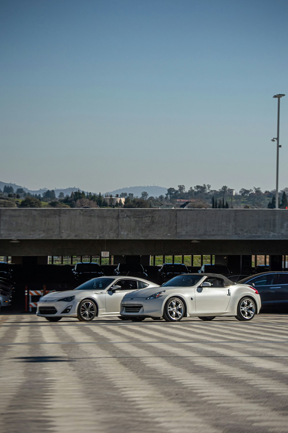 three cars parked in a parking lot under a bridge