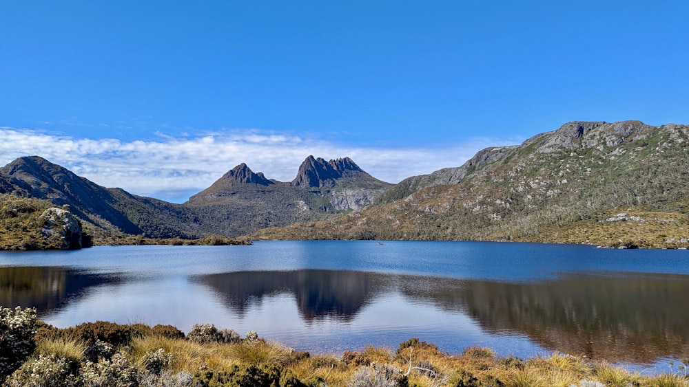 a lake surrounded by mountains and grass