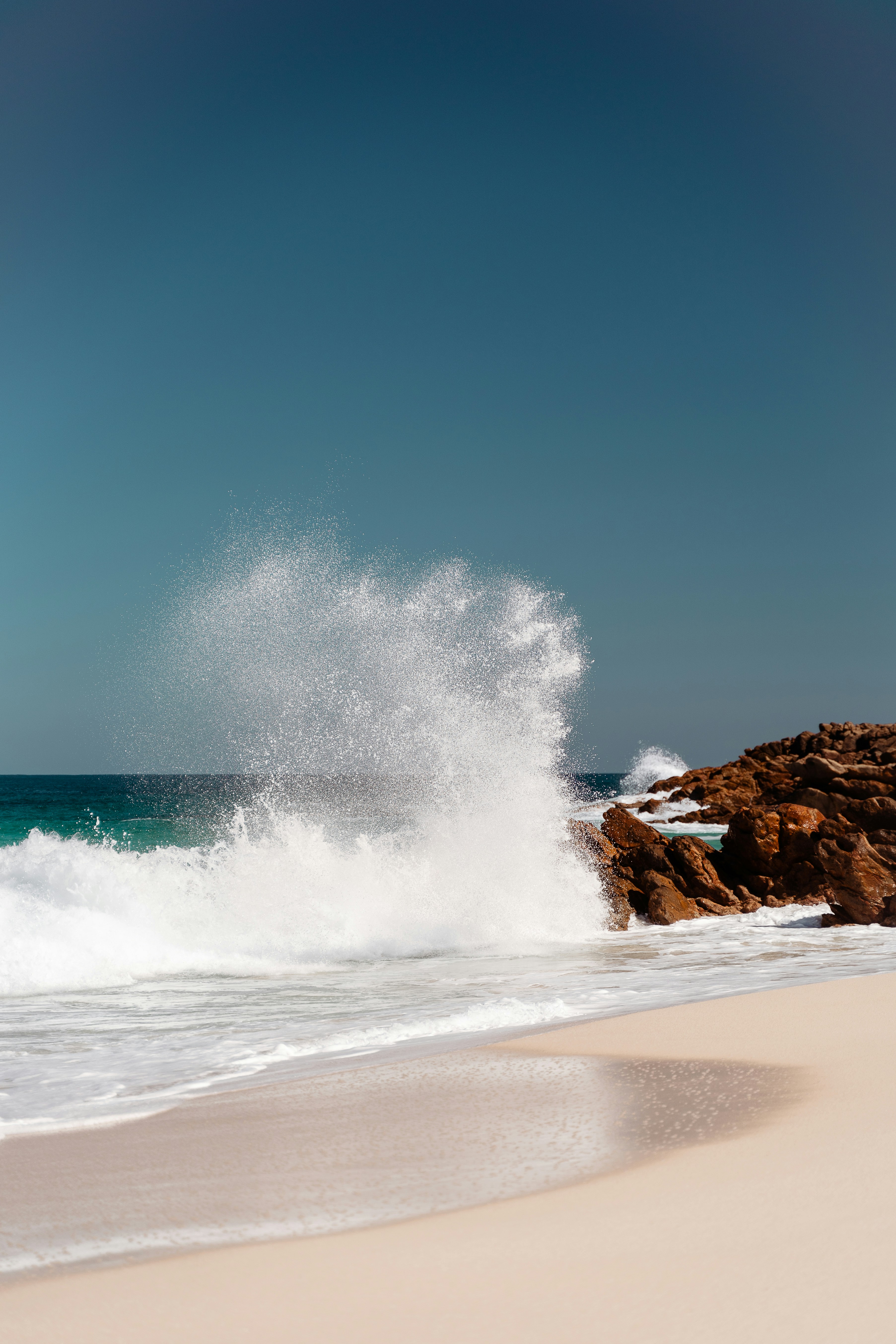 a large wave crashing into the shore of a beach