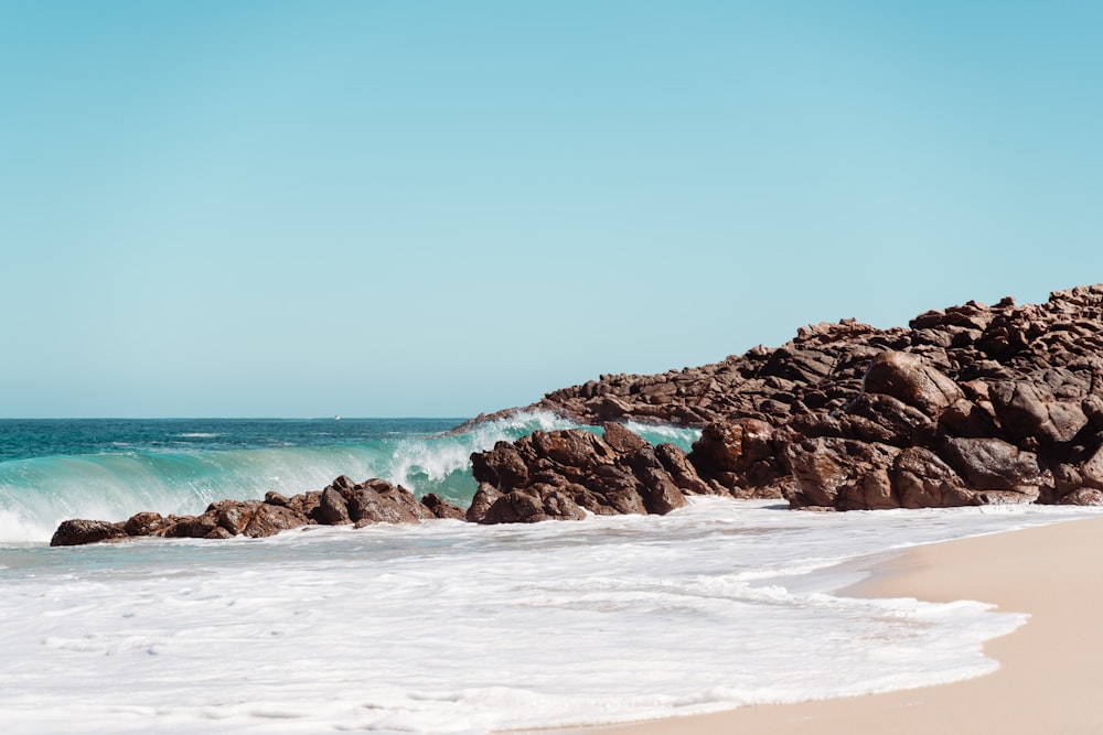 a rocky beach with a wave coming in to shore