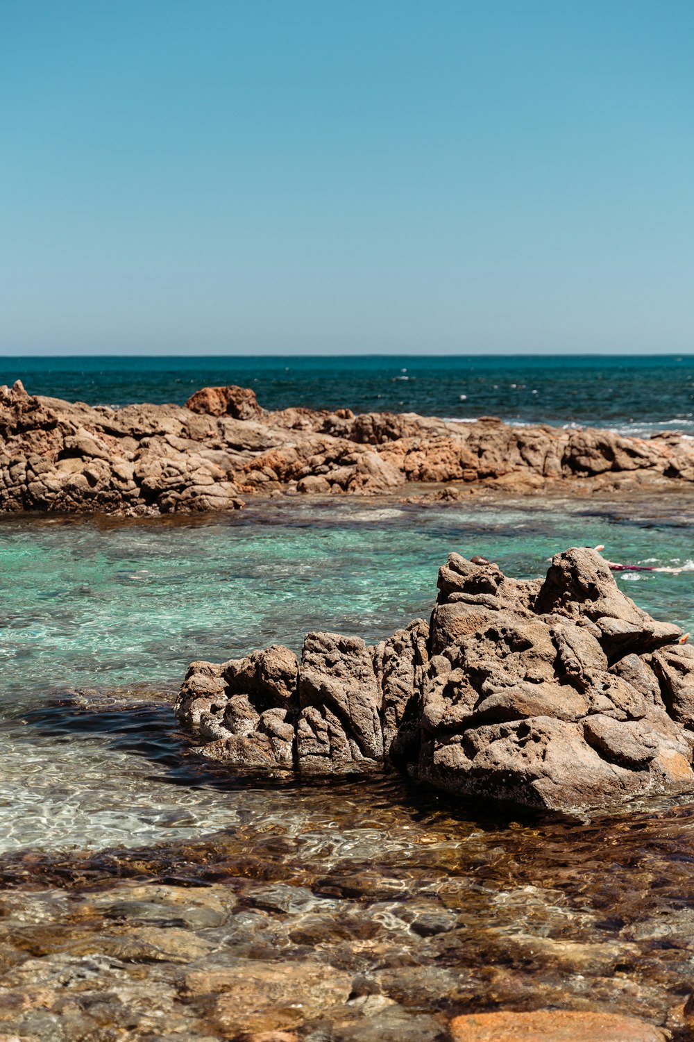 a rocky shore with clear blue water