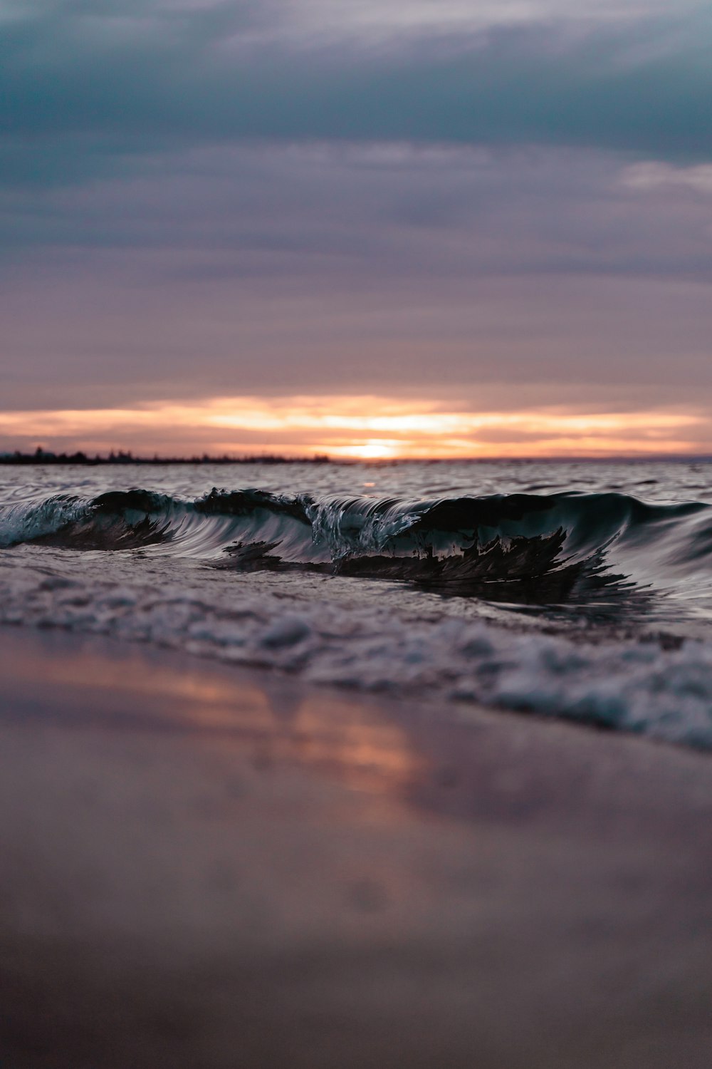 the sun is setting over the ocean waves