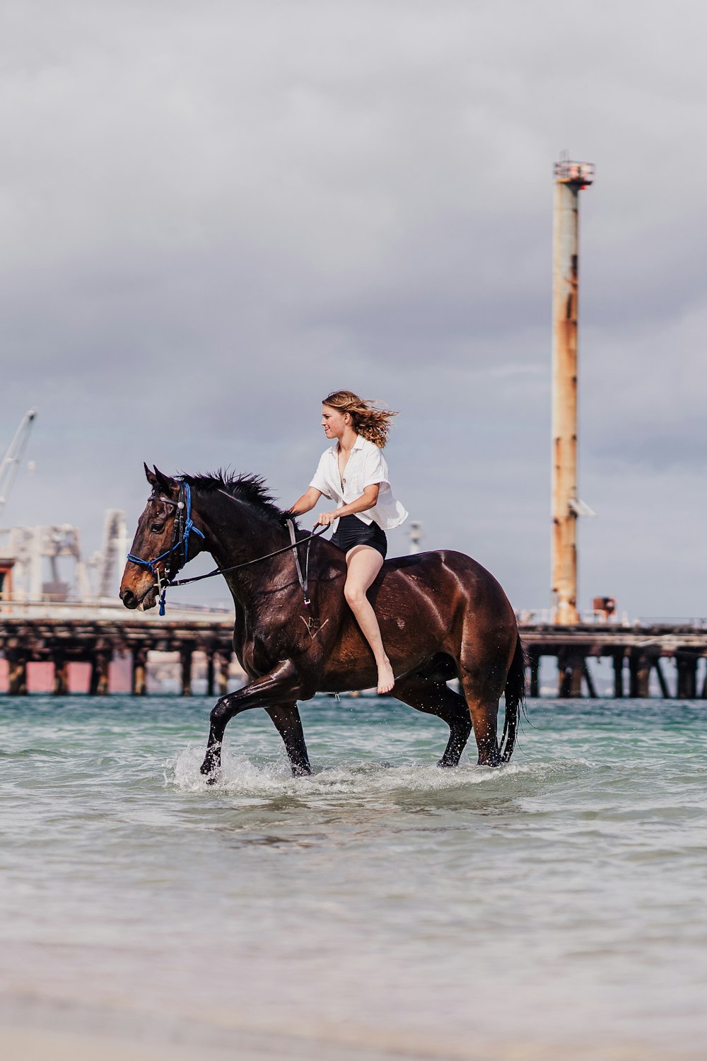 a woman riding a horse through the ocean