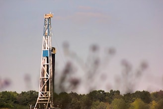 a drilling rig in a field with trees in the background