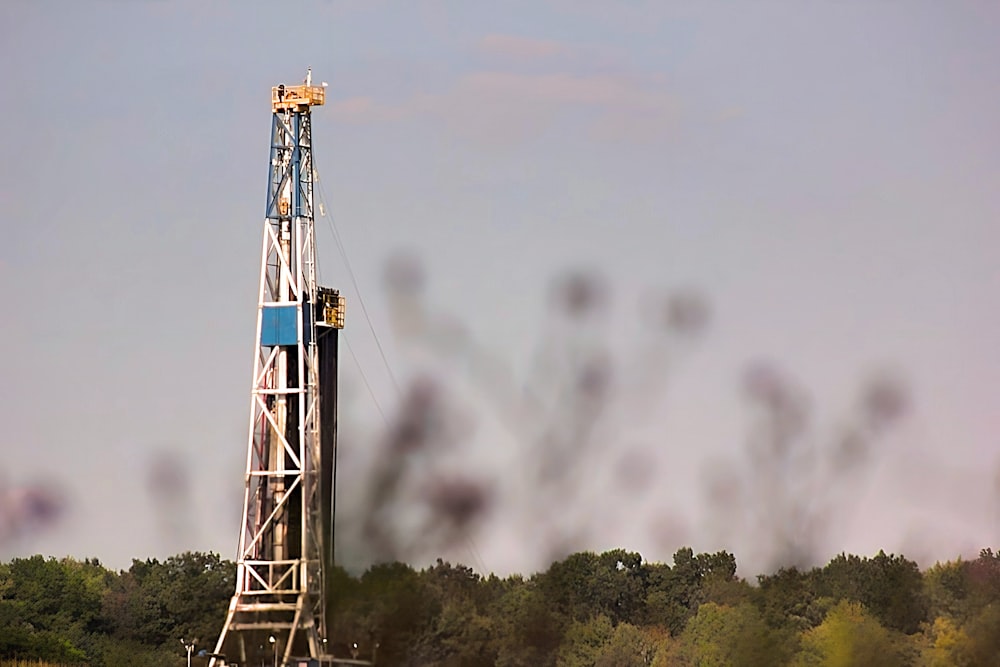 a drilling rig in a field with trees in the background