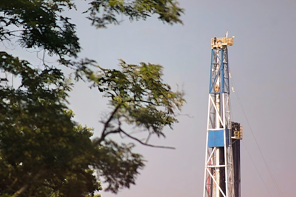 a blue and white drilling rig next to a tree