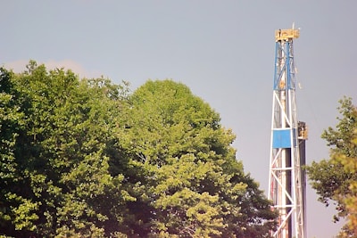 a blue and white drilling rig next to trees