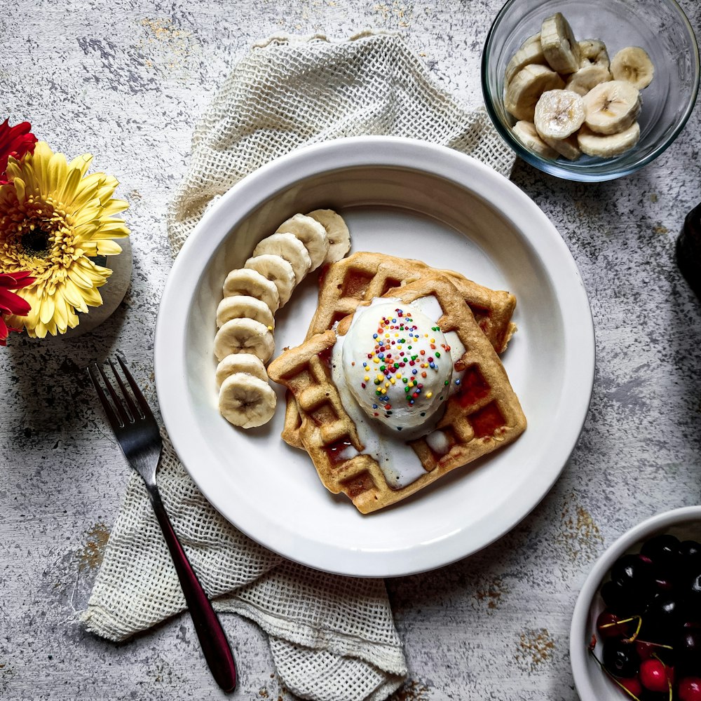 a plate of waffles with ice cream and bananas