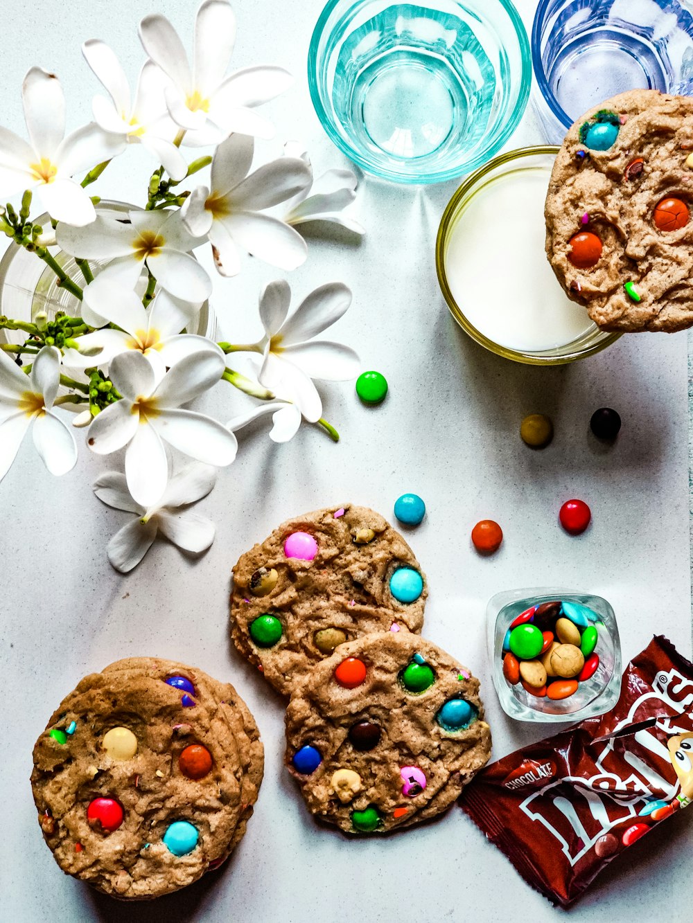 a table topped with cookies and candy next to a glass of milk